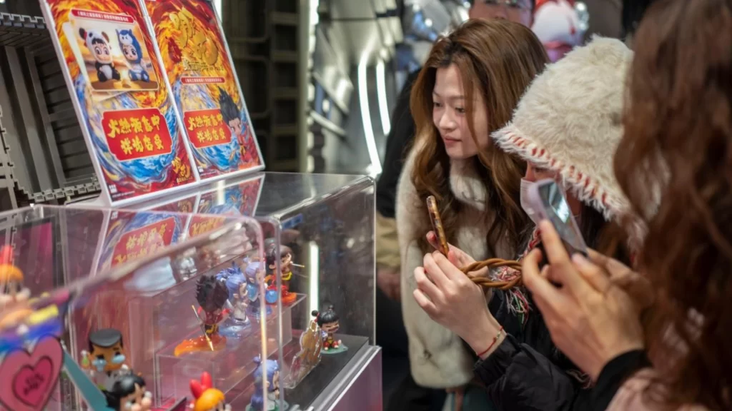 Fans photograph Ne Zha 2 figurines, showcasing China’s 2025 animation boom and IP commercial expansion.