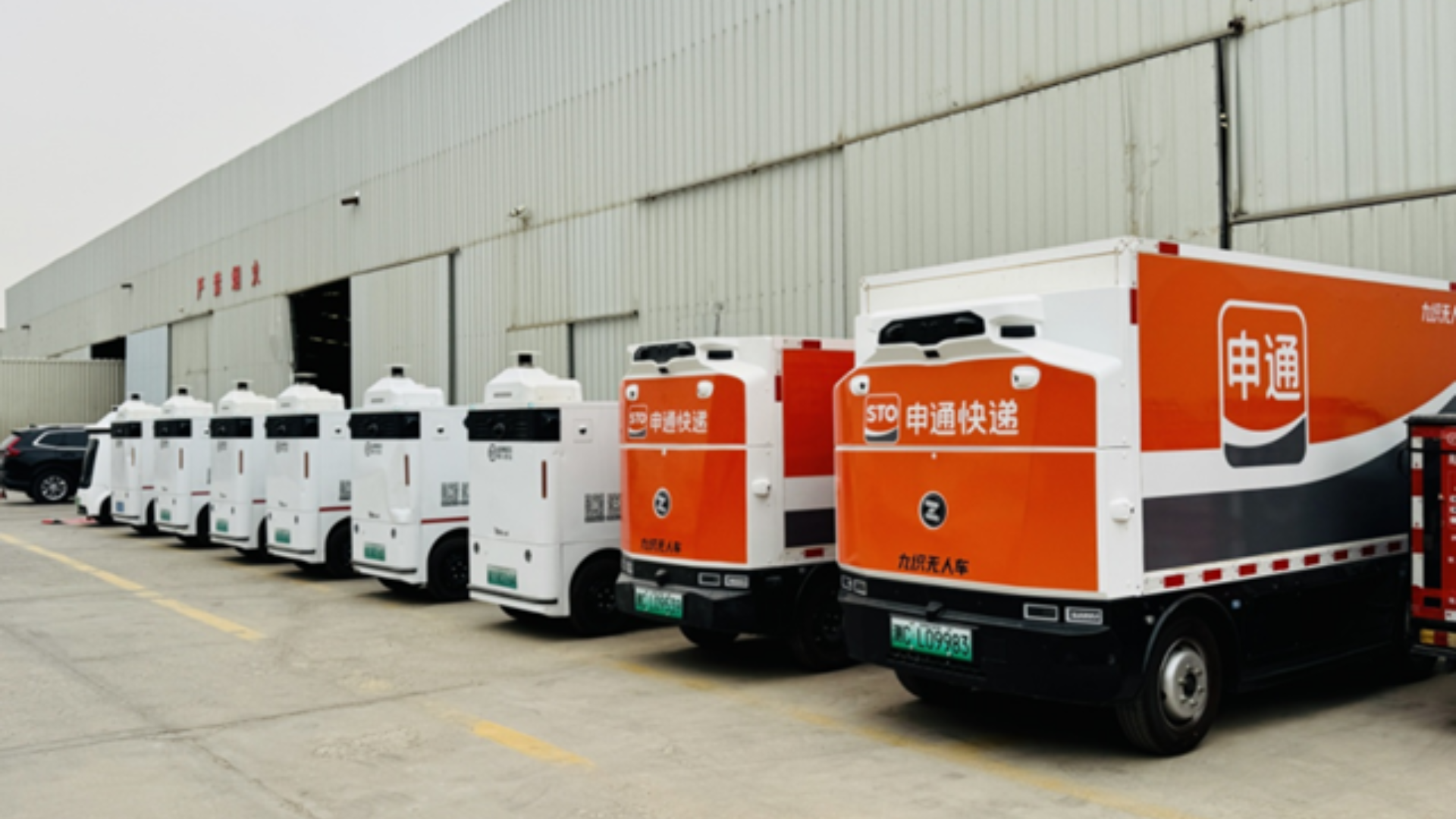 An orange autonomous vehicle delivers parcels to a smart rural station, boosting "last-mile" logistics efficiency.