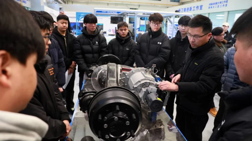 A group of young engineers studies mechanical components in a Zhengzhou high-tech innovation workshop.