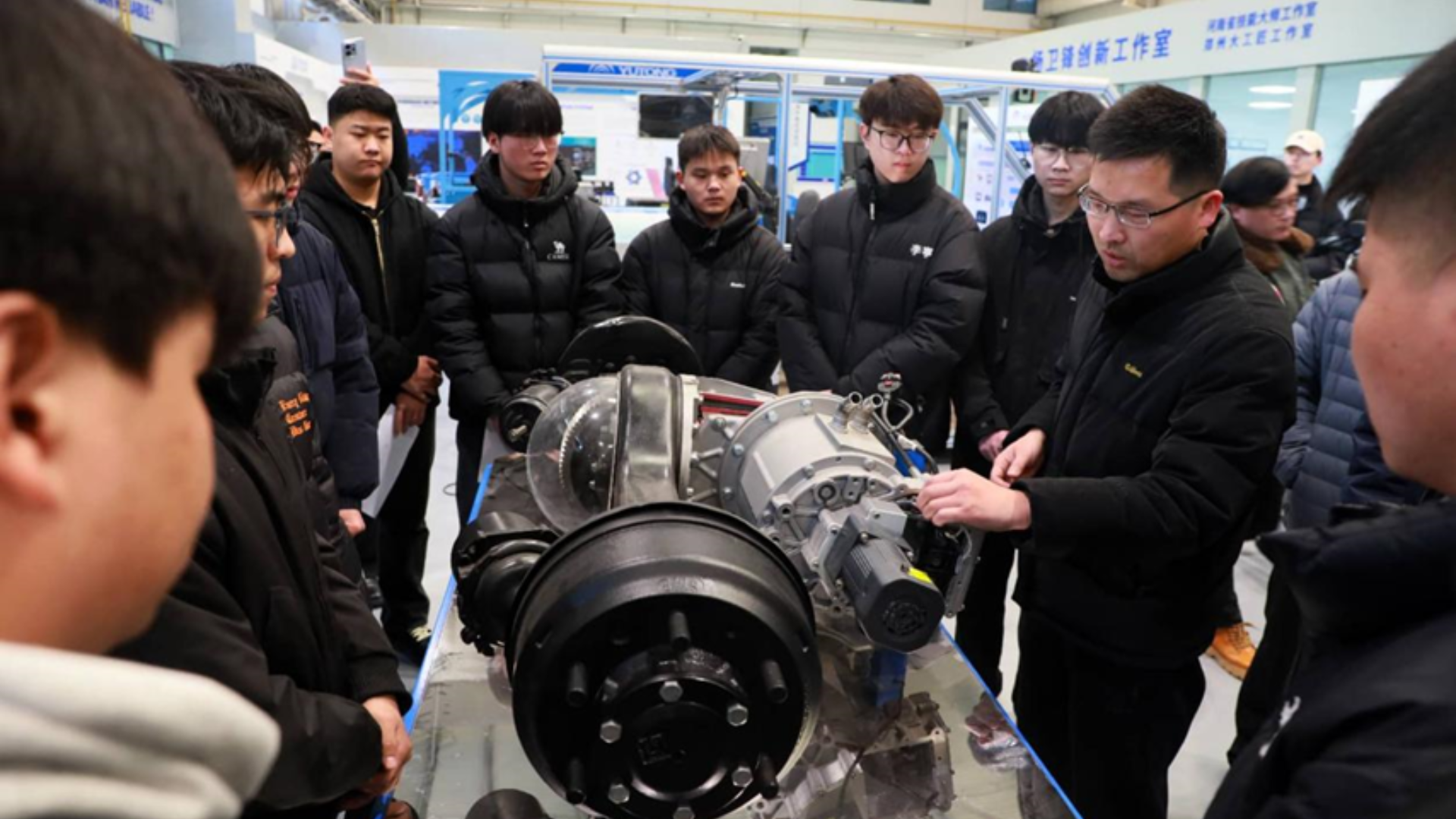 A group of young engineers studies mechanical components in a Zhengzhou high-tech innovation workshop.