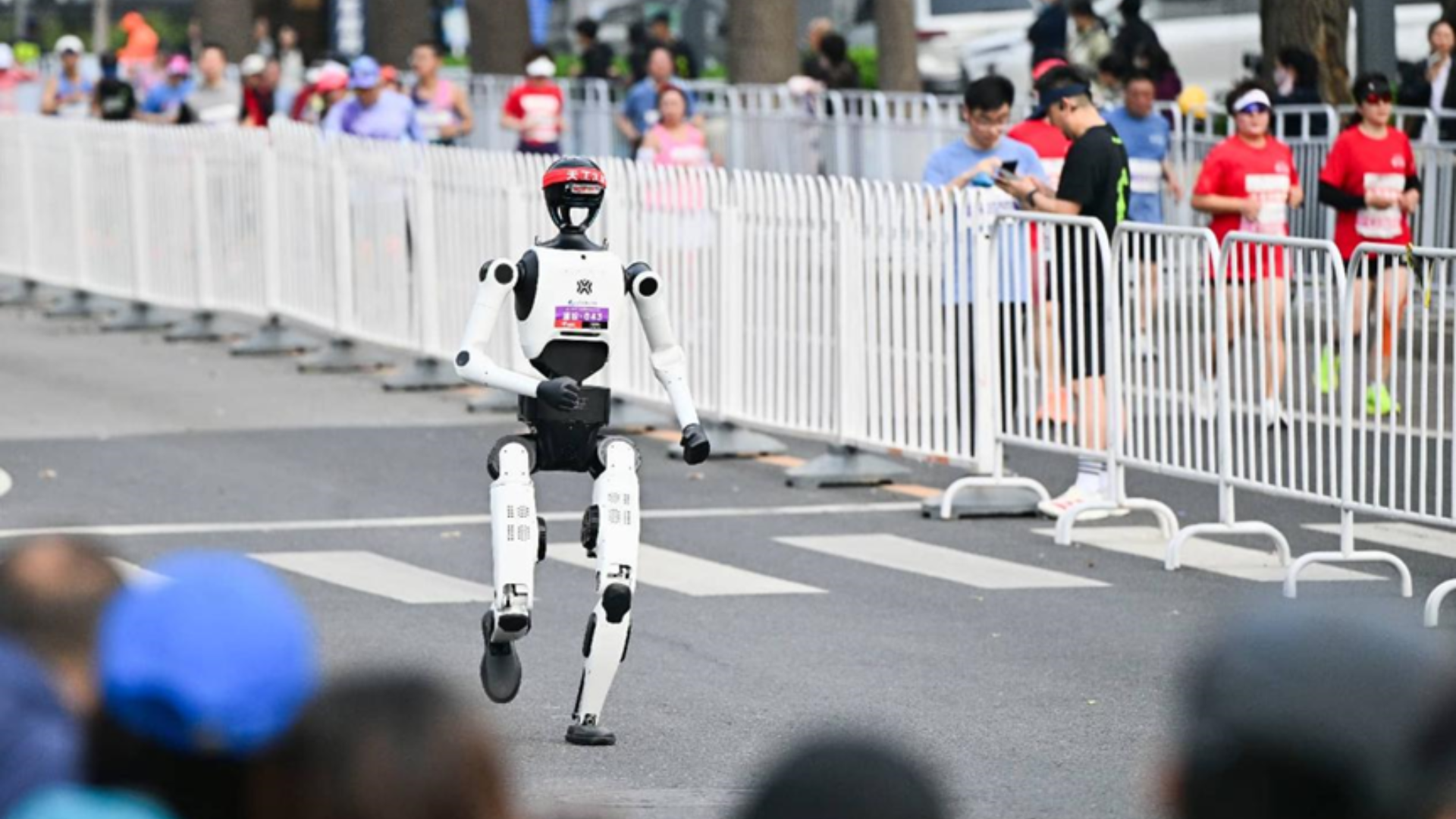 A humanoid robot wearing a red headband runs on a track during the Beijing half-marathon.