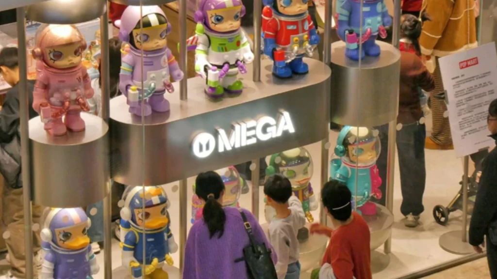 Shoppers browse colorful, designer astronaut figurines at a MEGA Pop Mart retail display.