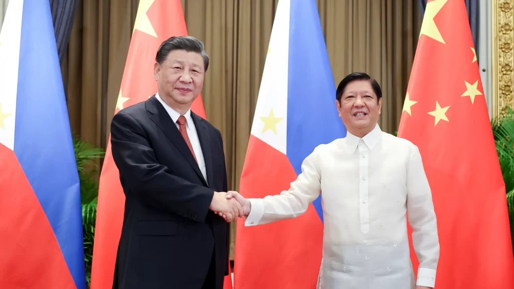Chinese and Philippine leaders shake hands in front of their national flags, symbolizing diplomatic dialogue.