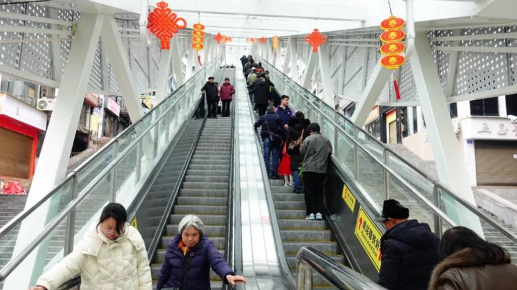 Commuters use a long, covered outdoor escalator system decorated with red lanterns in Wushan County.