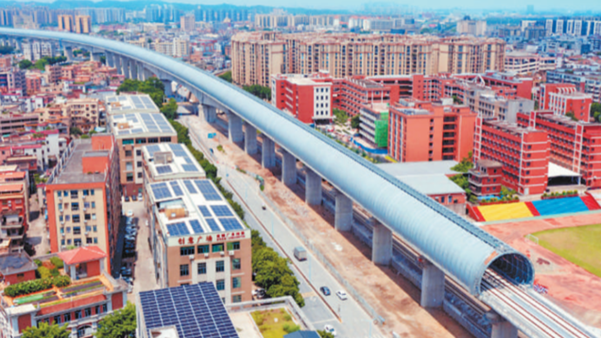 Aerial view of a high-speed railway enclosed in a fully soundproof tunnel through a city.