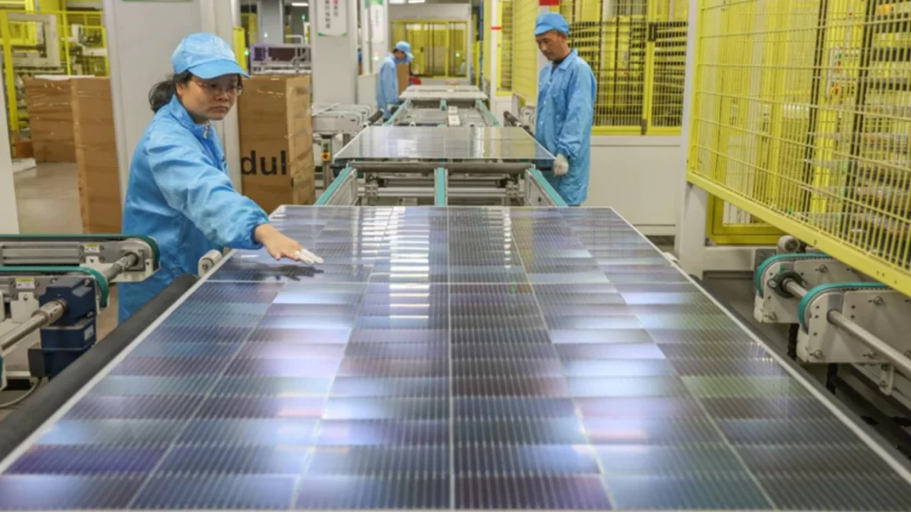 Workers in blue uniforms inspect solar panels on a high-tech automated production line in China.