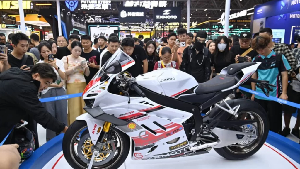 Crowds surrounding a white ZXMOTO sportbike, showcasing advanced Chinese engineering at an international exhibition.