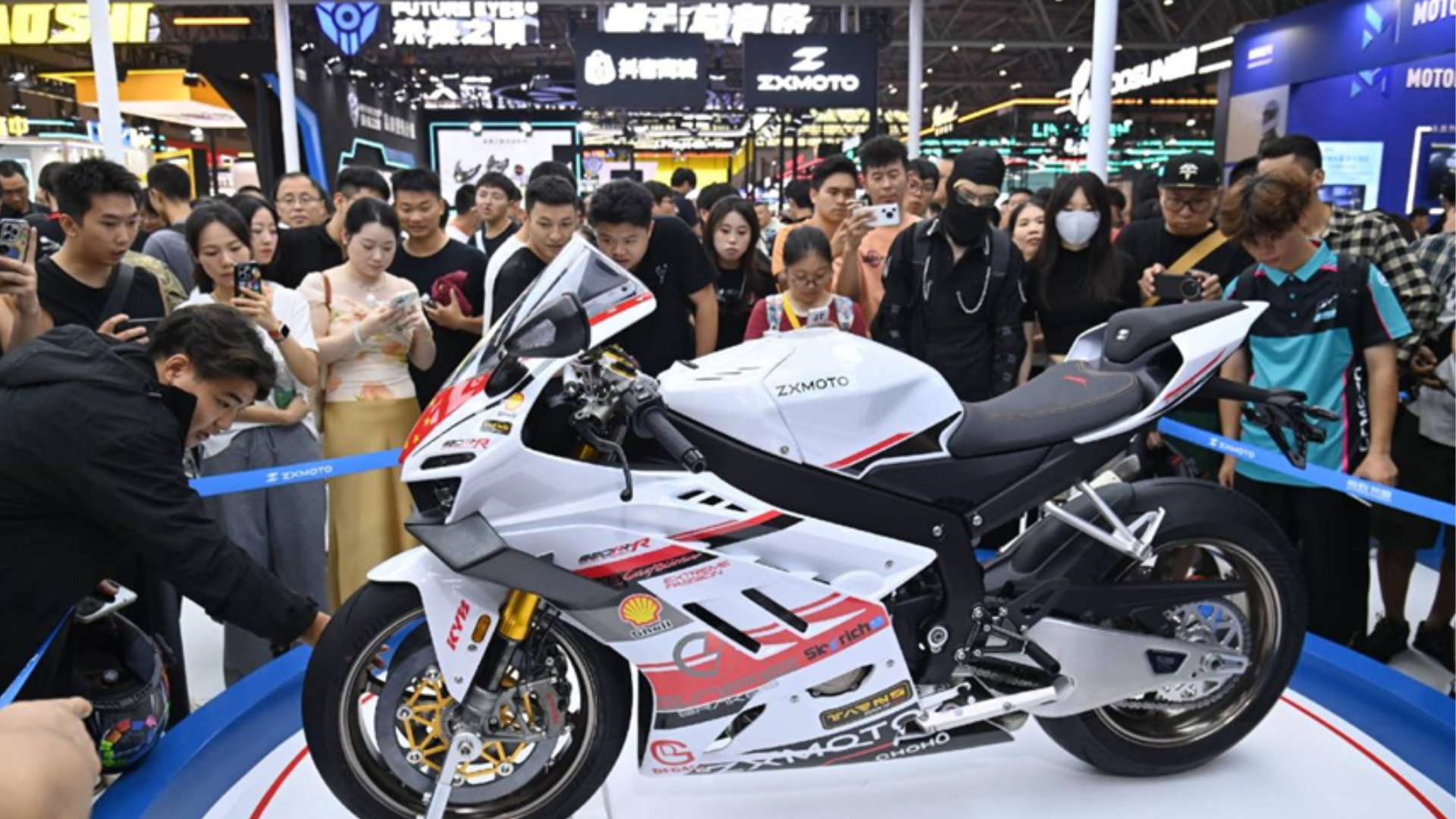 Crowds surrounding a white ZXMOTO sportbike, showcasing advanced Chinese engineering at an international exhibition.