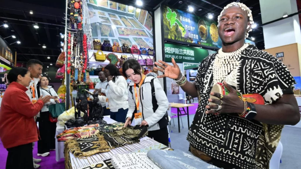 An African vendor promotes traditional textiles and handicrafts at a trade fair featuring zero-tariff goods.