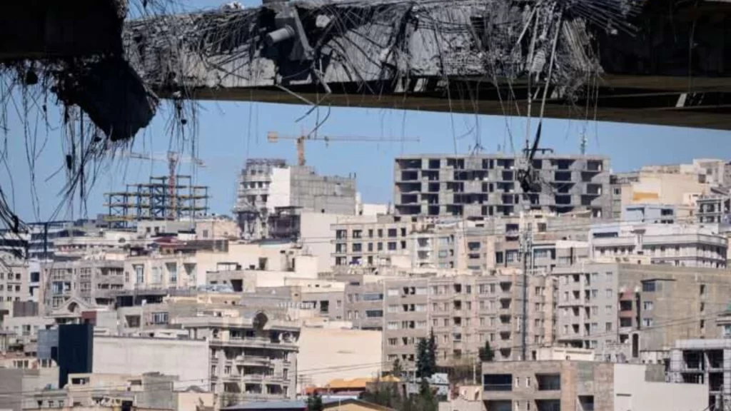 US F-15 jet wreckage in Iran with search teams and smoke rising from nearby infrastructure.