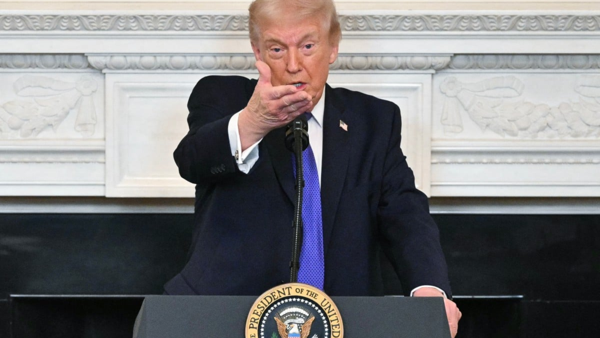 President Donald Trump at a lectern announcing a naval blockade of the Strait of Hormuz.