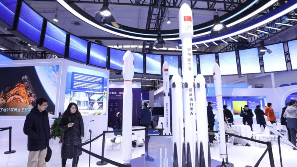 Visitors viewing models of Chinese commercial rockets at an indoor aerospace technology exhibition.