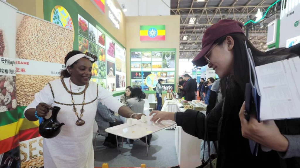 An Ethiopian exhibitor serving coffee to a visitor at a trade fair booth.
