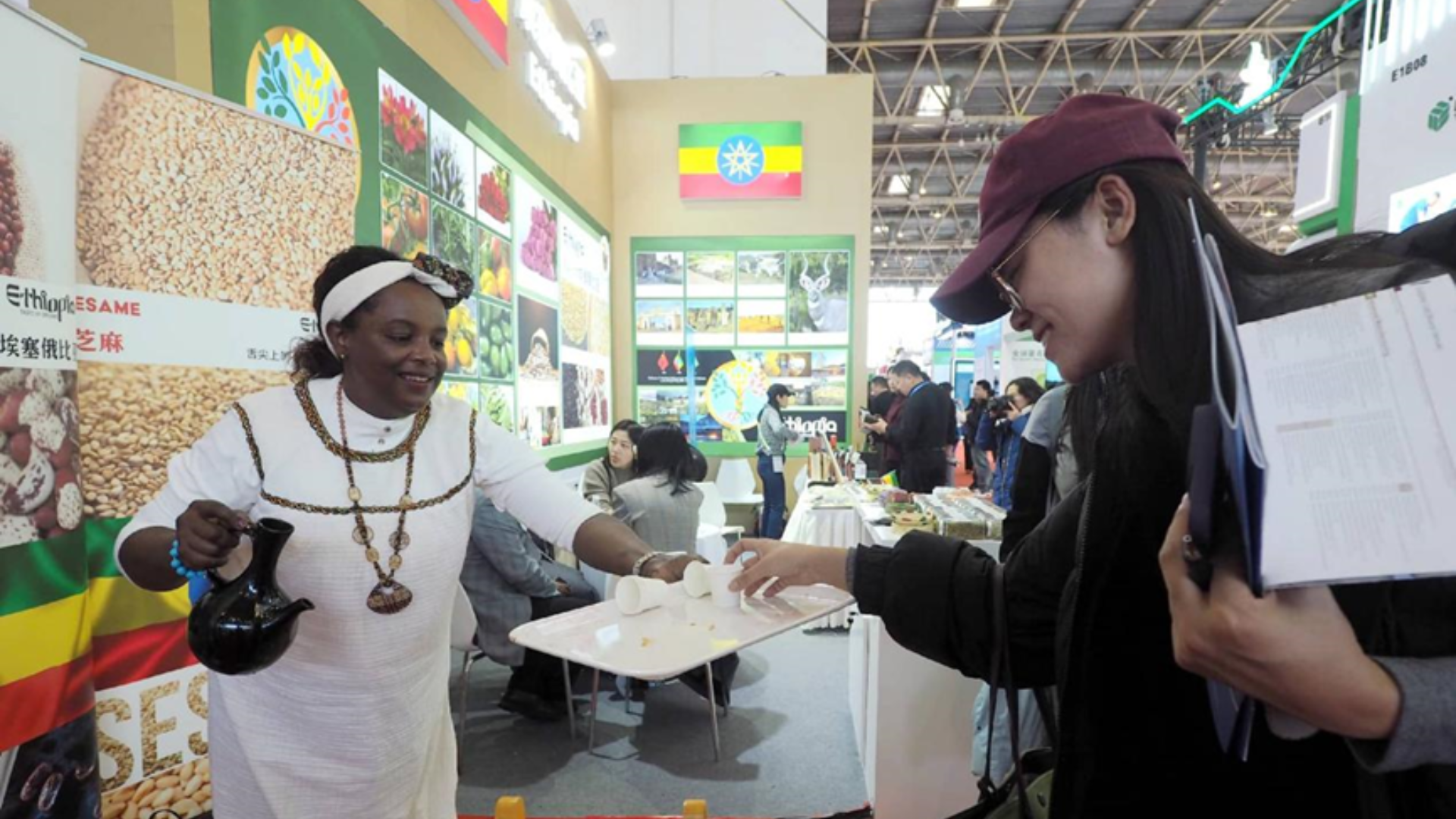 An Ethiopian exhibitor serving coffee to a visitor at a trade fair booth.