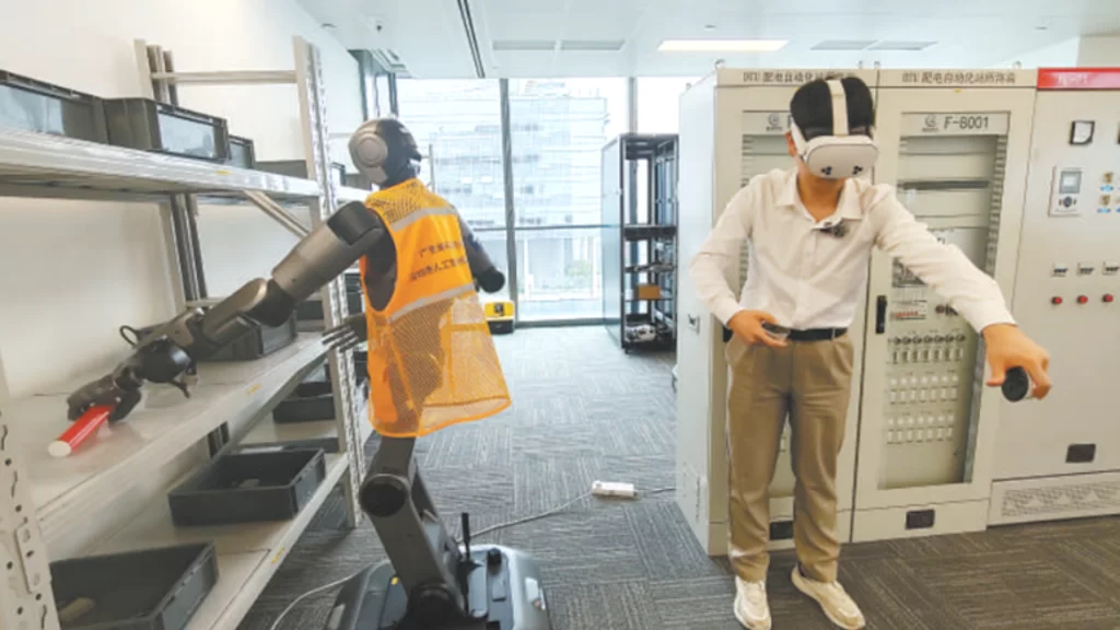 A young engineer wearing a VR headset remotely teleoperating a humanoid robot in a training lab.