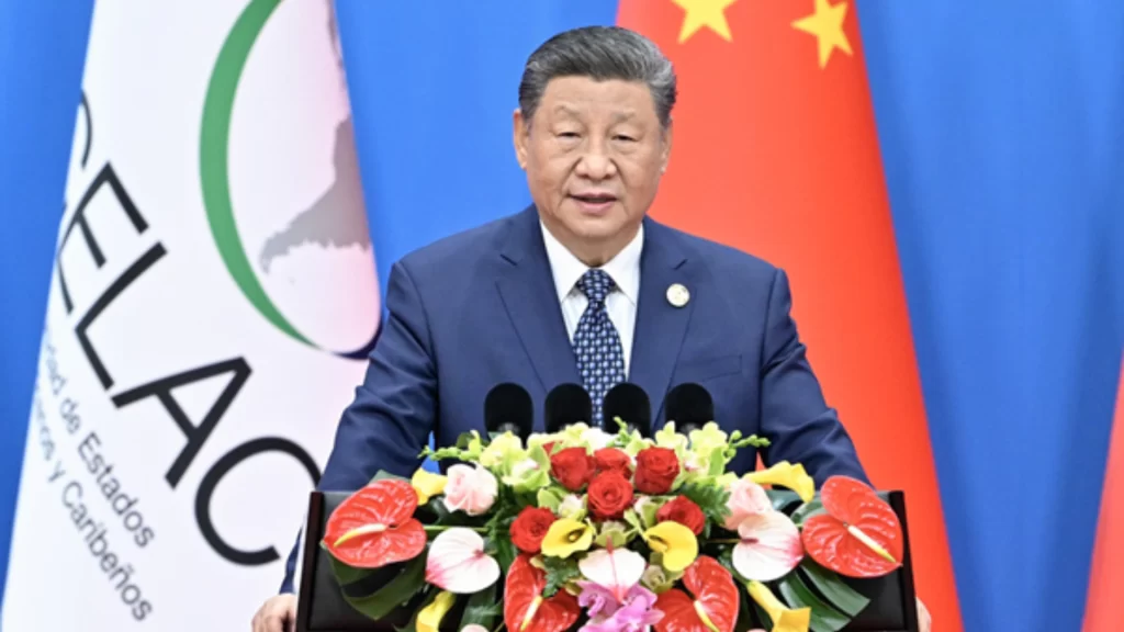 President Xi Jinping delivers a speech behind a floral arrangement and national flags.