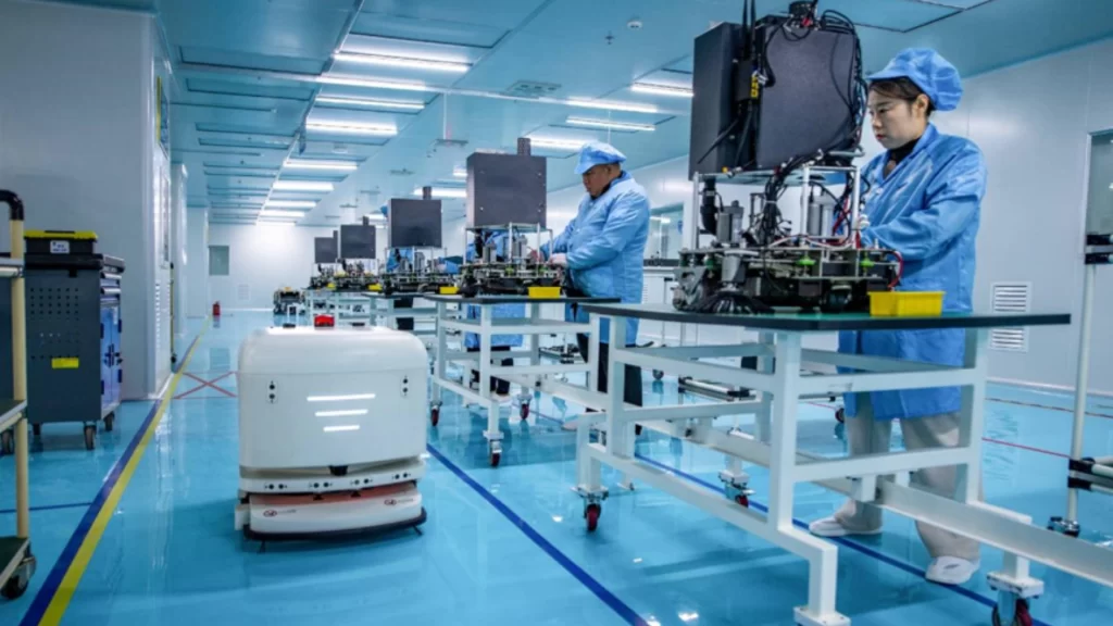 Chinese workers assemble intelligent cleaning robots, highlighting innovation-driven growth in advanced manufacturing exports.