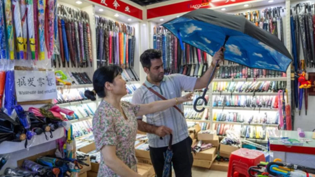 Customer examines innovative Chinese umbrellas in Yiwu showroom showcasing smart, premium and customized designs.