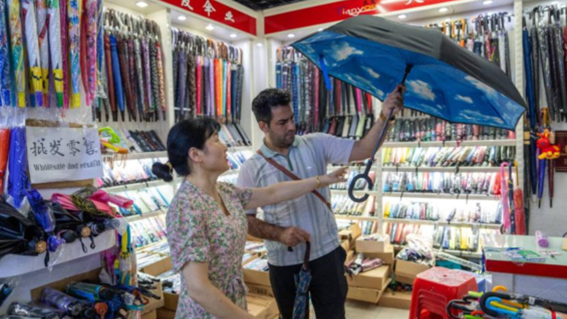 Customer examines innovative Chinese umbrellas in Yiwu showroom showcasing smart, premium and customized designs.