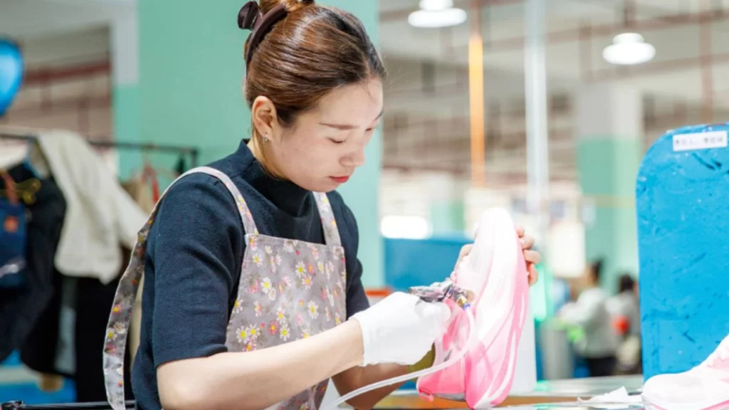 Factory worker crafting Chinese running shoes amid booming global cross-border e-commerce growth.