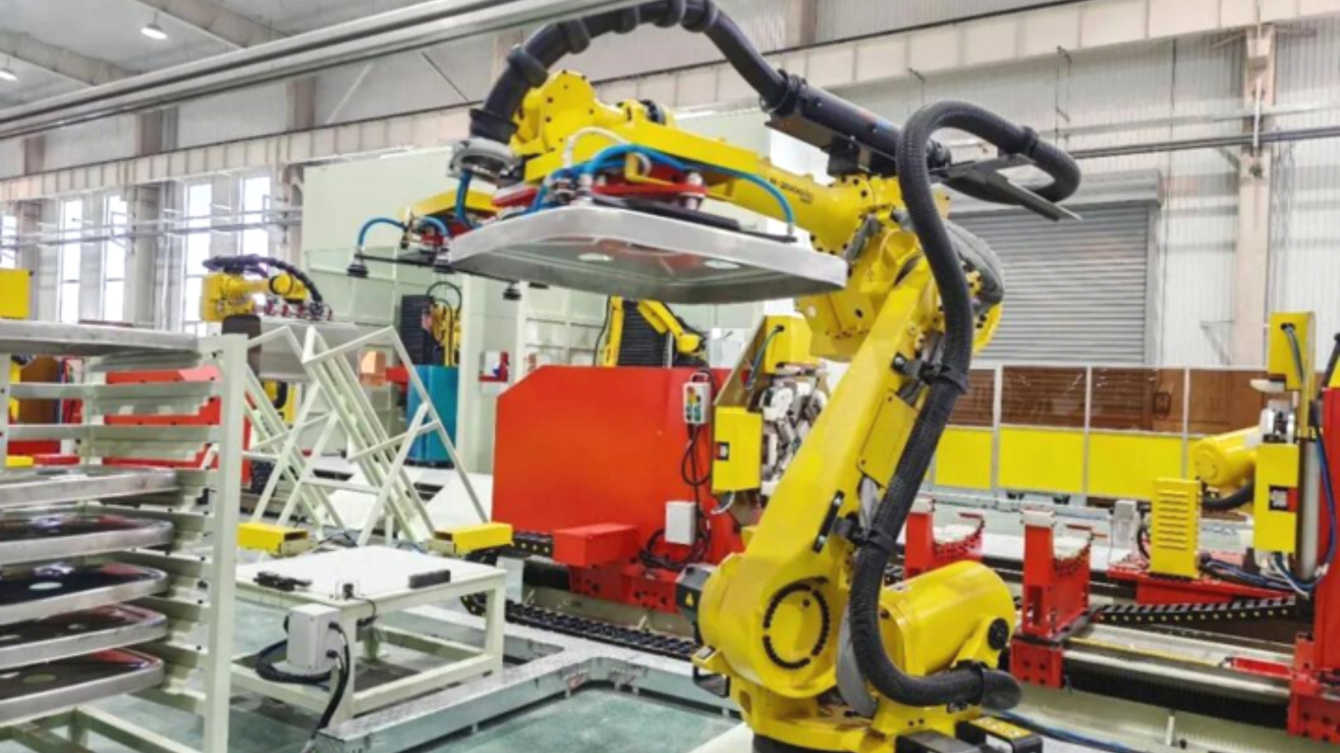 Yellow intelligent robotic arms operating inside a shared manufacturing factory.