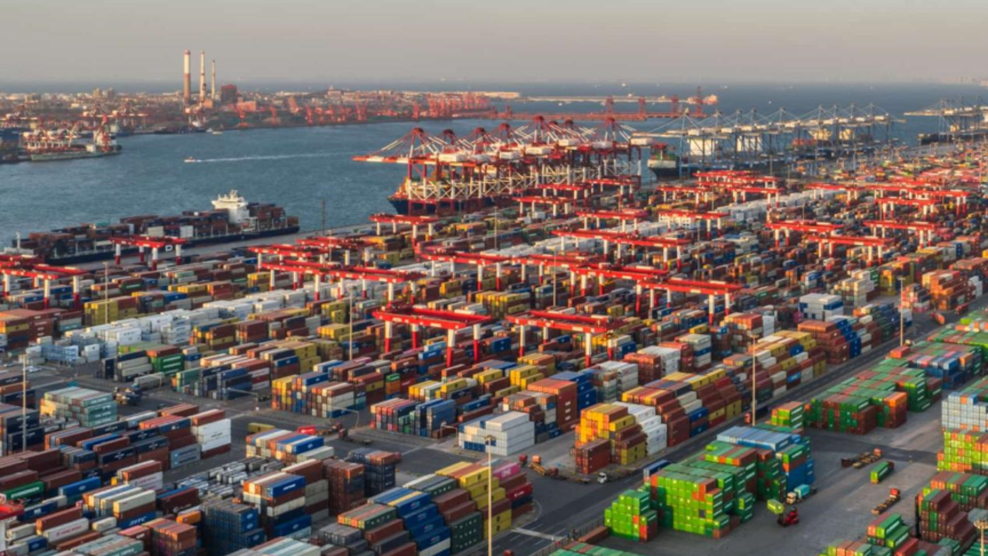 A vast, bustling automated terminal with colorful stacked shipping containers and cargo cranes.