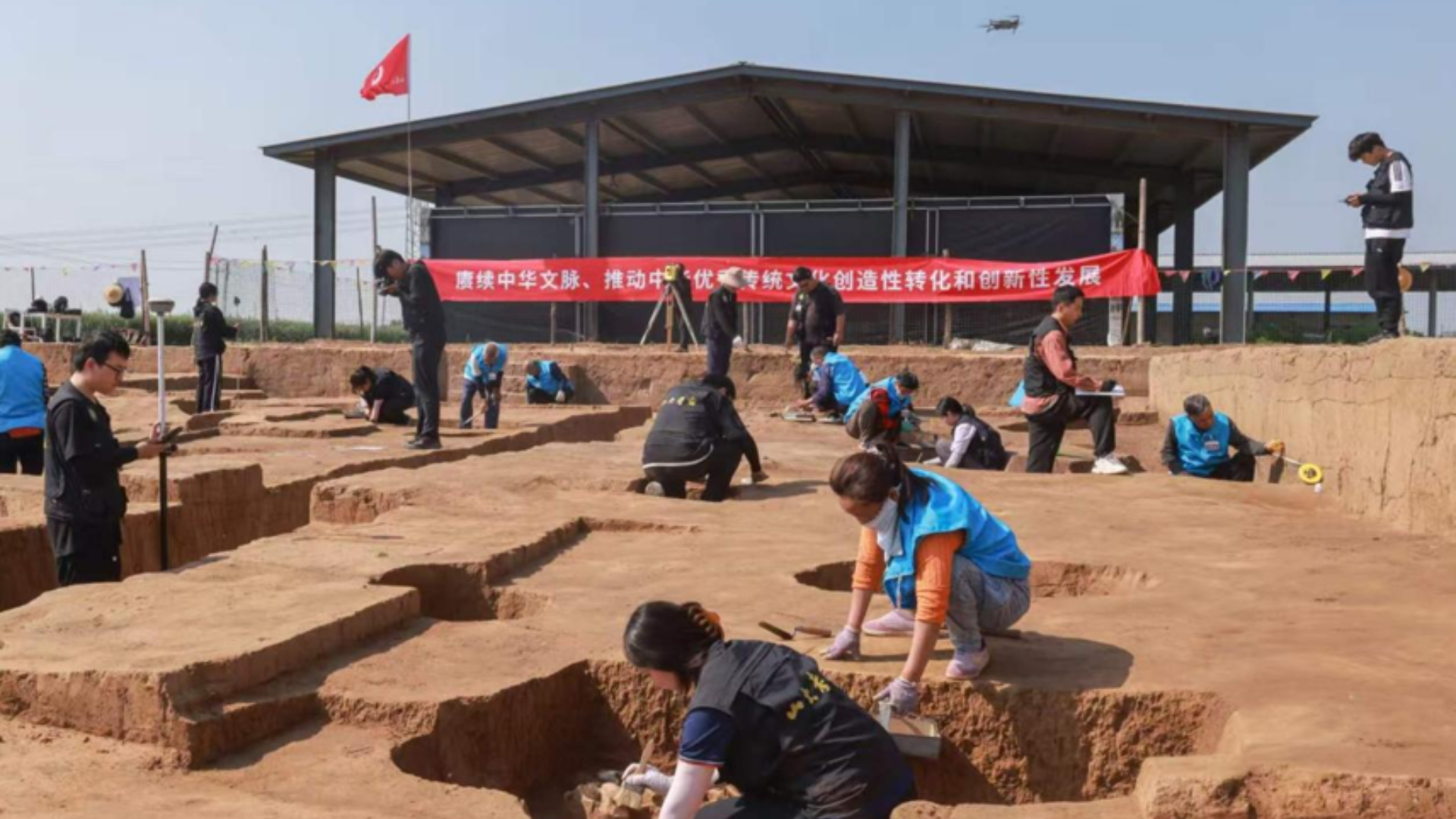 Researchers and students excavate pits at an open-air archaeological field site in China.