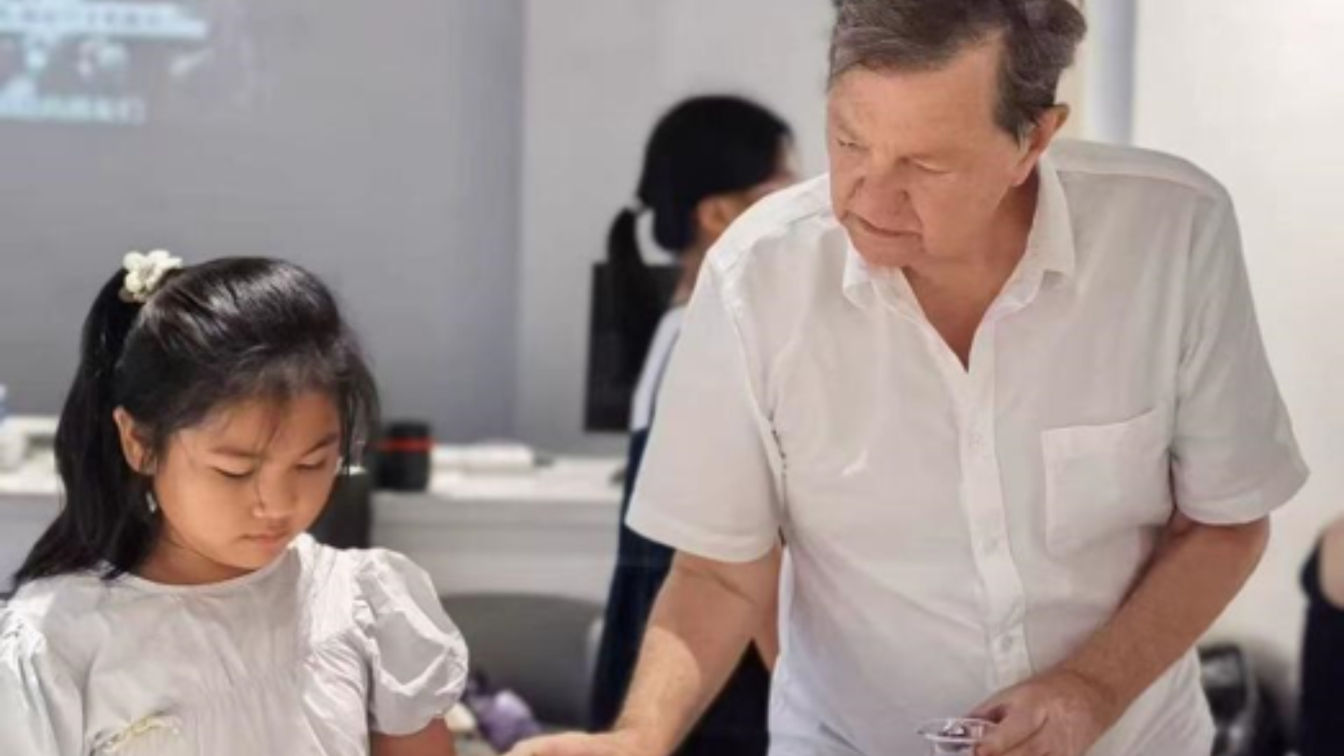Australian artist David Reid paints with a local child, highlighting Jingdezhen's inclusive cross-cultural exchange.