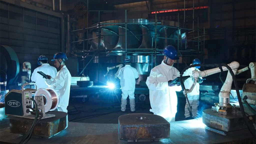 Workers operate collaborative welding robots, advancing smart manufacturing and industrial innovation.