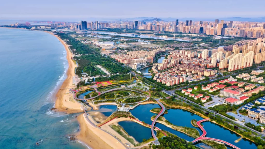 Aerial view of Rizhao coastline showcasing marina, eco-restoration, tourism and clear coastal waters.