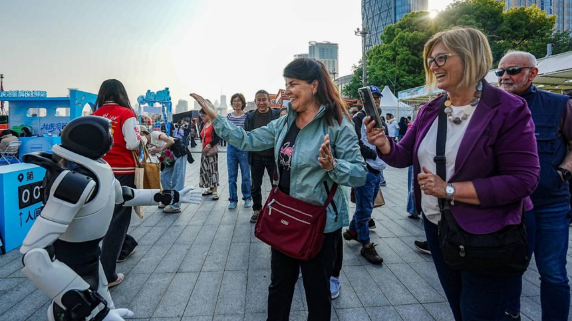 Foreign tourists interact with humanoid robot at Shanghai's North Bund, showcasing smart tourism innovation.