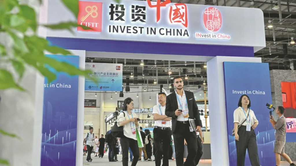 Attendees walk past the "Invest in China" pavilion showcasing the country's foreign investment efforts.