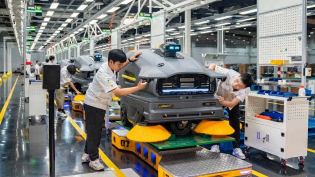 Technicians inspecting cleaning robots on an assembly line reflecting booming Chinese robotics exports.